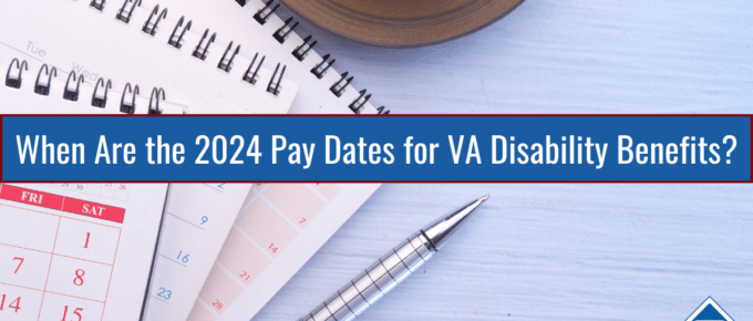 Two calendars are stacked on top of each other in the upper left hand corner. A silver pen is lying next to the calendars. Part of a saucer with a mug peeks from the top center. Article title runs across the middle of the photo: When are the 2024 Pay Dates for VA Disability Benefits?