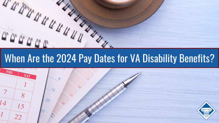 Two calendars are stacked on top of each other in the upper left hand corner. A silver pen is lying next to the calendars. Part of a saucer with a mug peeks from the top center. Article title runs across the middle of the photo: When are the 2024 Pay Dates for VA Disability Benefits?