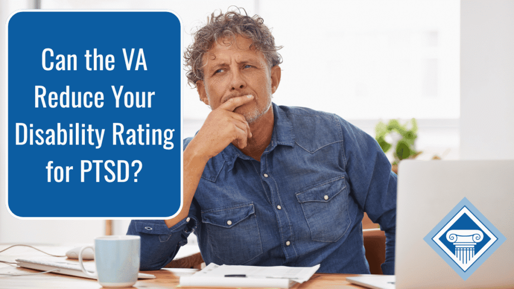 Photo of a man with curly gray hair and a denim button-up sitting at a desk with a coffee cup, documents, and a laptop, and the article title is in the upper left hand corner: Can the VA Reduce Your Disability Rating for PTSD?