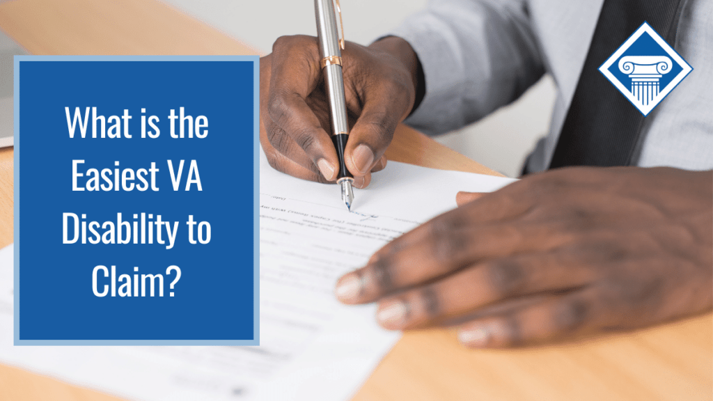 An image of a person's hands over a desk, writing on a piece of paper. Over the image is a blue box reading the article title: What is the easiest VA disability claim?