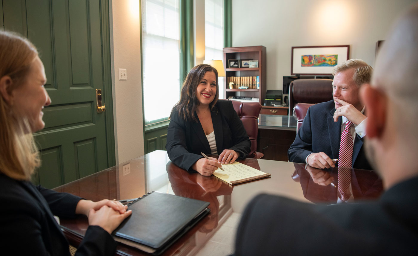 Woods and Woods Lawyers Krystal Lechner, Lori Underwood, Neil Woods, and Zach Evans in a meeting talking about VA disability.