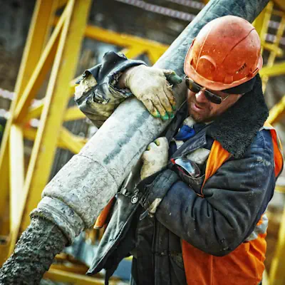 A man holds and directs a pipe pumping concrete.