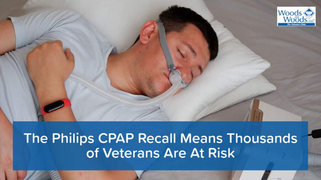 Picture of a man sleeping with a CPAP machine on his nose. Our Woods and Woods logo is in the top right and our title is at the bottom: The Philips CPAP Recall Means Thousands of Veterans Are At Risk