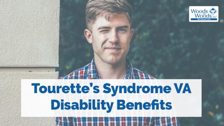 A picture of a blond man in a red, white, and blue checkered shirt with one eye winking uncontrollably. Our title is in front of him: Tourette's Syndrome VA disability Benefits.